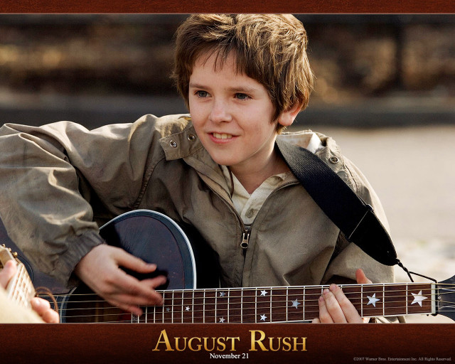Young boy playing guitar smiling free wallpaper - medium preview image