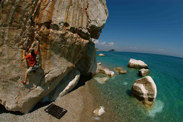 Man climbing cliff ocean beach free wallpaper - medium preview image