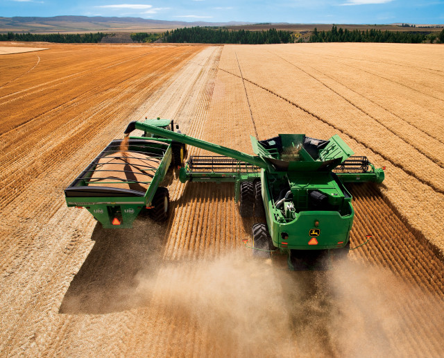 Green tractor driving field grain free wallpaper - medium preview image