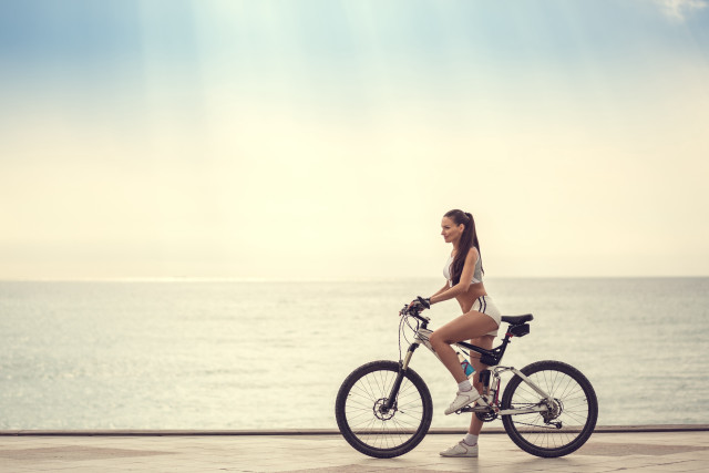 Woman biking ocean sunny day free wallpaper - medium preview image