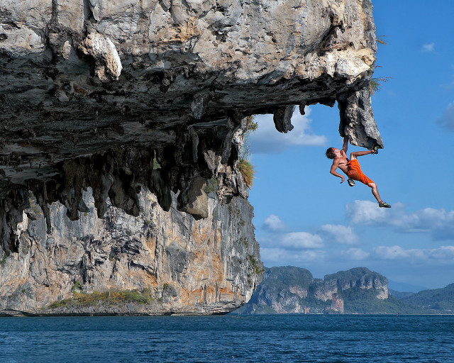 Man jumping cliff ocean background free wallpaper - medium preview image