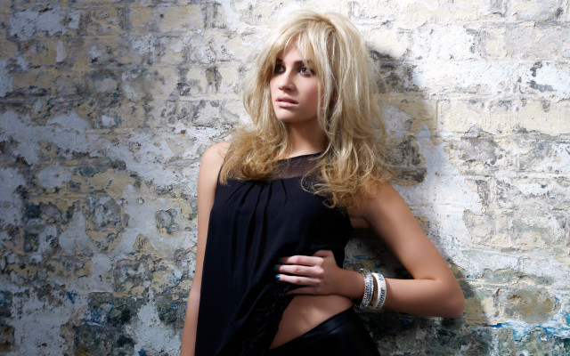 Blond woman standing against wall free wallpaper - medium preview image