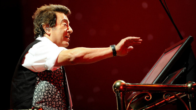 Man standing piano arm outstretched free wallpaper - medium preview image