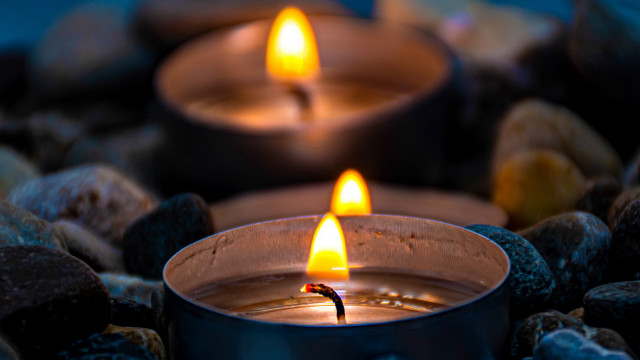 Lit candle rocks blue background free wallpaper - medium preview image