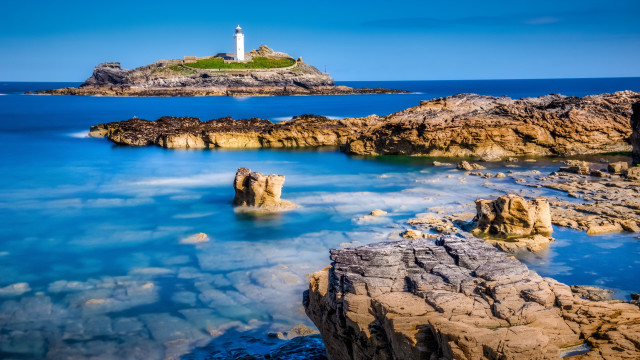 Lighthouse rocky shore blue water free wallpaper - medium preview image