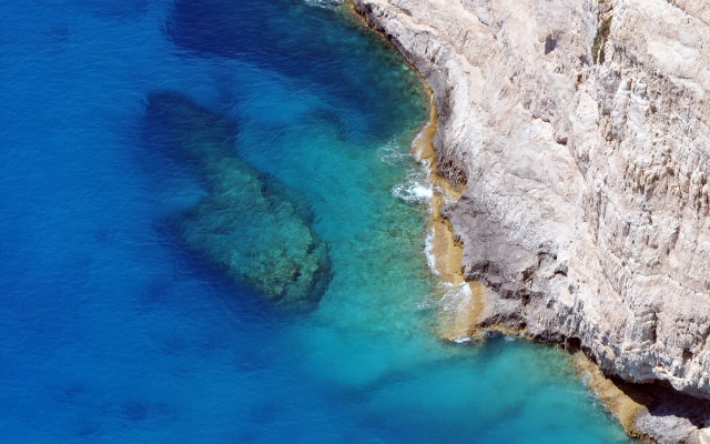 Rocky cliff blue water aerial free wallpaper - medium preview image
