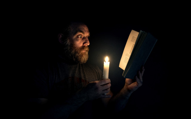 Man holding book candle dark free wallpaper - medium preview image
