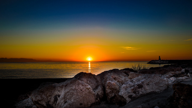 Sunset lighthouse rocks boat water free wallpaper - medium preview image