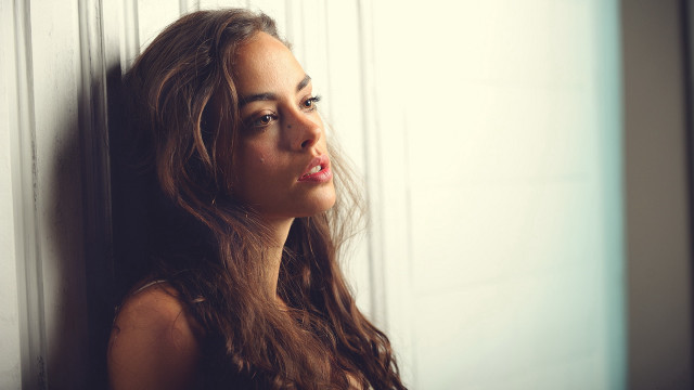 Woman leaning wall serious portrait #5 free wallpaper - medium preview image