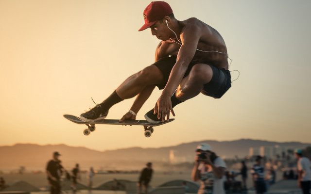 Skateboarder flying crowd beach sunset free wallpaper - medium preview image