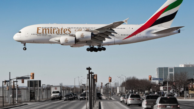 Emirates jetliner over busy street free wallpaper - medium preview image
