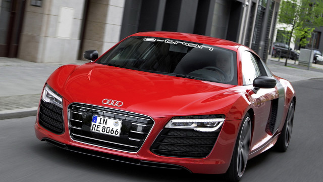 Red car driving tall building free wallpaper - medium preview image
