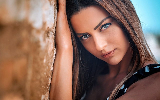 Woman leaning wall serious portrait #2 free wallpaper - medium preview image