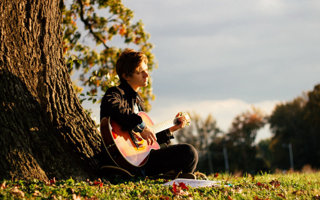 Man sitting under tree playing free wallpaper - medium preview image
