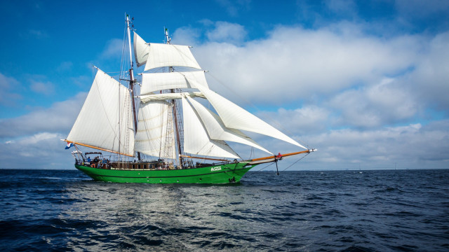 Green sailboat ocean cloudy day free wallpaper - medium preview image