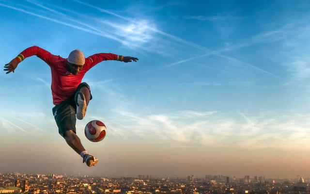 Man jumping soccerball city background free wallpaper - medium preview image