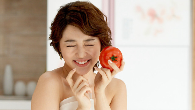 Woman holding tomato smiling camera free wallpaper - medium preview image