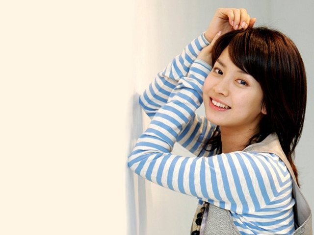 Smiling woman leaning wall hand free wallpaper - medium preview image