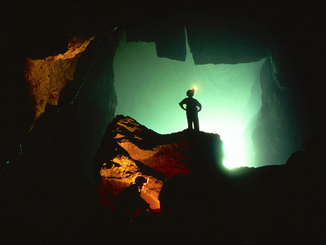 Man standing cliff cave flashlight free wallpaper - medium preview image