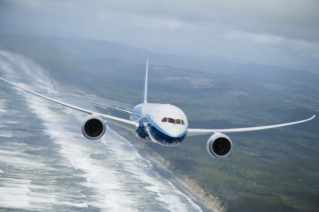 Jetliner flying green hillside ocean free wallpaper - medium preview image