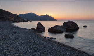 Beach rocks bird sunset mountains - the background and a body of water free wallpaper
