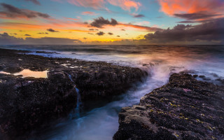 Sunset rocky beach waterfall cloudy - a sunset over a rocky beach free wallpaper