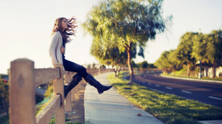 Woman sitting fence hair blowing - a wooden fence free wallpaper