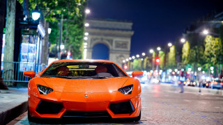 Bright orange sports car night - night time in a city free wallpaper