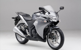 Silver motorcycle parked white surface - a gray background free wallpaper