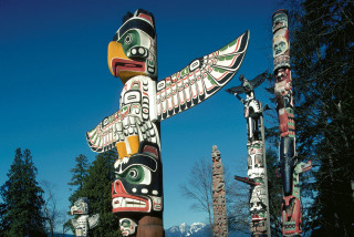 Totem pole sculpture mountain forest - side and a mountain in the background free wallpaper