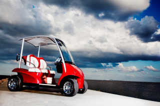 Red golf cart ocean cloudy - a dark sky in the background free wallpaper