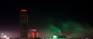 Tall building green light night - a city skyline in the background free wallpaper