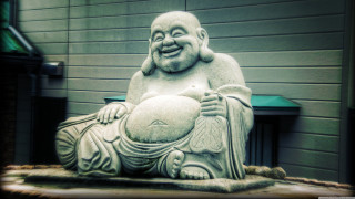 Laughing buddha statue green door - a bench in front free wallpaper