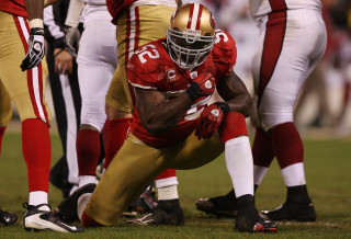 Football player kneeling field hands - his hands in his pockets free wallpaper