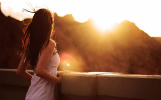 Woman ledged hair blowing sunshine - a mountain range in the background free wallpaper