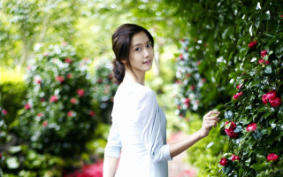 Woman standing bush flowers smiling - her face free wallpaper