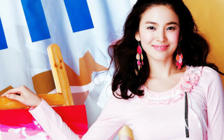 Woman pink shirt earrings posing - a chair in front free wallpaper