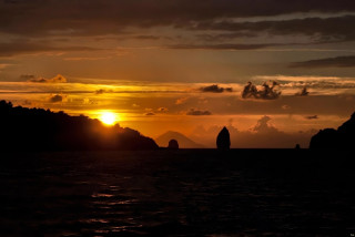 Sunset water mountain boat person - a mountain in the background and a boat free wallpaper