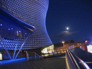 Curved roof building blue light - a full moon in the distance free wallpaper