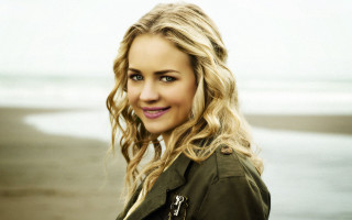 Blonde woman green jacket beach - a gray sky in the background free wallpaper