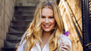 Woman holding purple flower smiling - cheerful free wallpaper