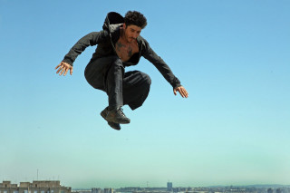 Man flying skateboard city park - building free wallpaper
