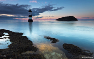 Lighthouse rocky beach ocean sunset - cloudy free wallpaper