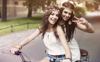 Girls bike peace sign smiling - a building in the background free wallpaper
