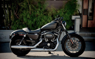 Motorcycle parked building green bush - a motorcycle free wallpaper