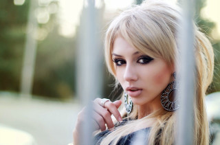 Woman long hair big earrings - behind a fence free wallpaper
