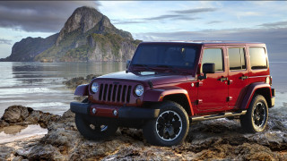 Red jeep rocky beach ocean 2 - a mountain in the background and a body of water free wallpaper