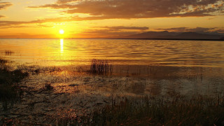 Sunset over water boat mountains - a sunset over a body of water free wallpaper