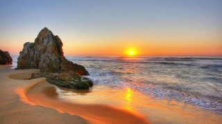 Sunset ocean rock formation beach 3 - a rock formation in the foreground free wallpaper