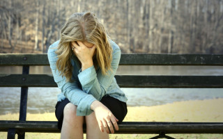 Woman sitting bench head hands - a body of water free wallpaper